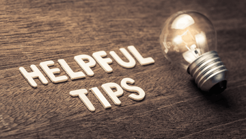 Wooden letters spelling helpful tips next to a glowing light bulb on wooden surface